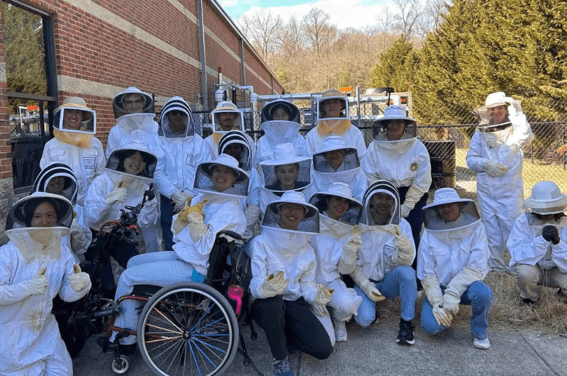 Students in the beekeeping club post with their beekeeping suits on